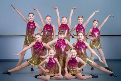 Young girls in sparkly dance costumes posing in a studio.