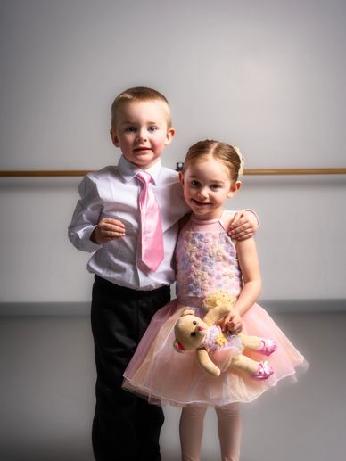 Young boy and girl dressed formally, smiling together.