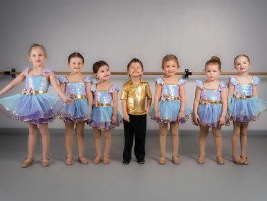 Young children in ballet costumes posing together in a studio.