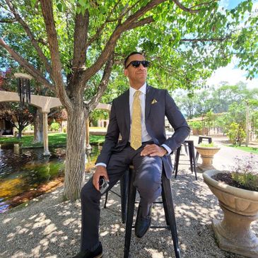 Person wearing a suit and sunglasses sitting on stool at a wedding party near Moab Utah