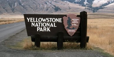 Yellowstone National Park entrance sign with mountainous backdrop.
