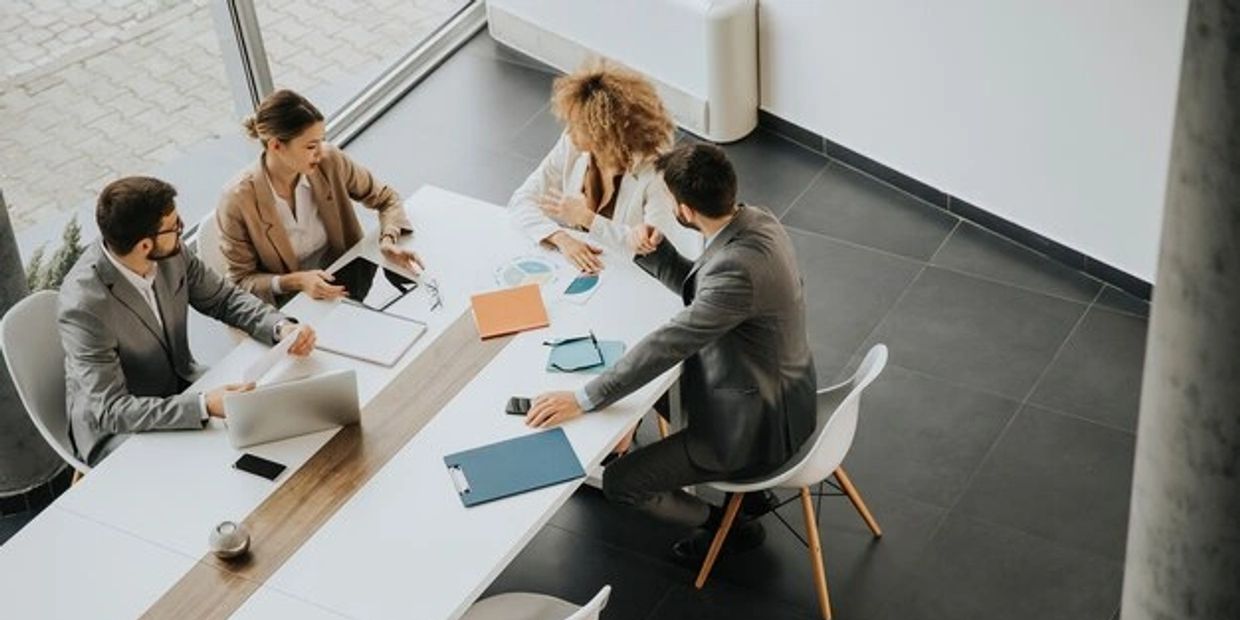 Diverse people (two men and two women) in a meeting in a conference room. 