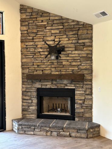 Rustic fireplace mantel on cultured stone. 