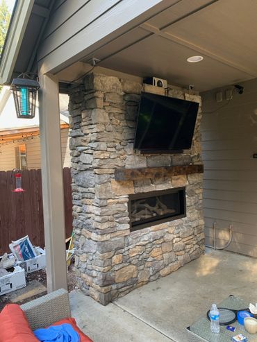 Rustic fireplace mantel on an outdoor fireplace with TV