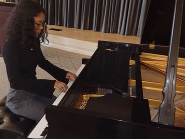 Girl learning piano with teacher