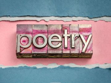 Word ‘poetry’ spelled with textured letter blocks on a pink and blue background