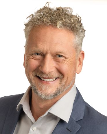 Smiling middle-aged man with curly hair in suit.