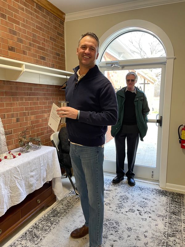 Smiling church member standing in the inside hallway by the church entrance door.