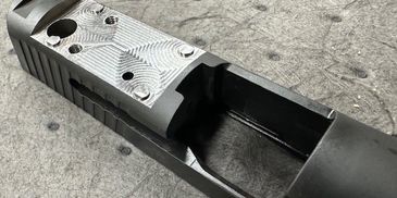 Close-up of a custom-machined firearm slide with detailed milling patterns.