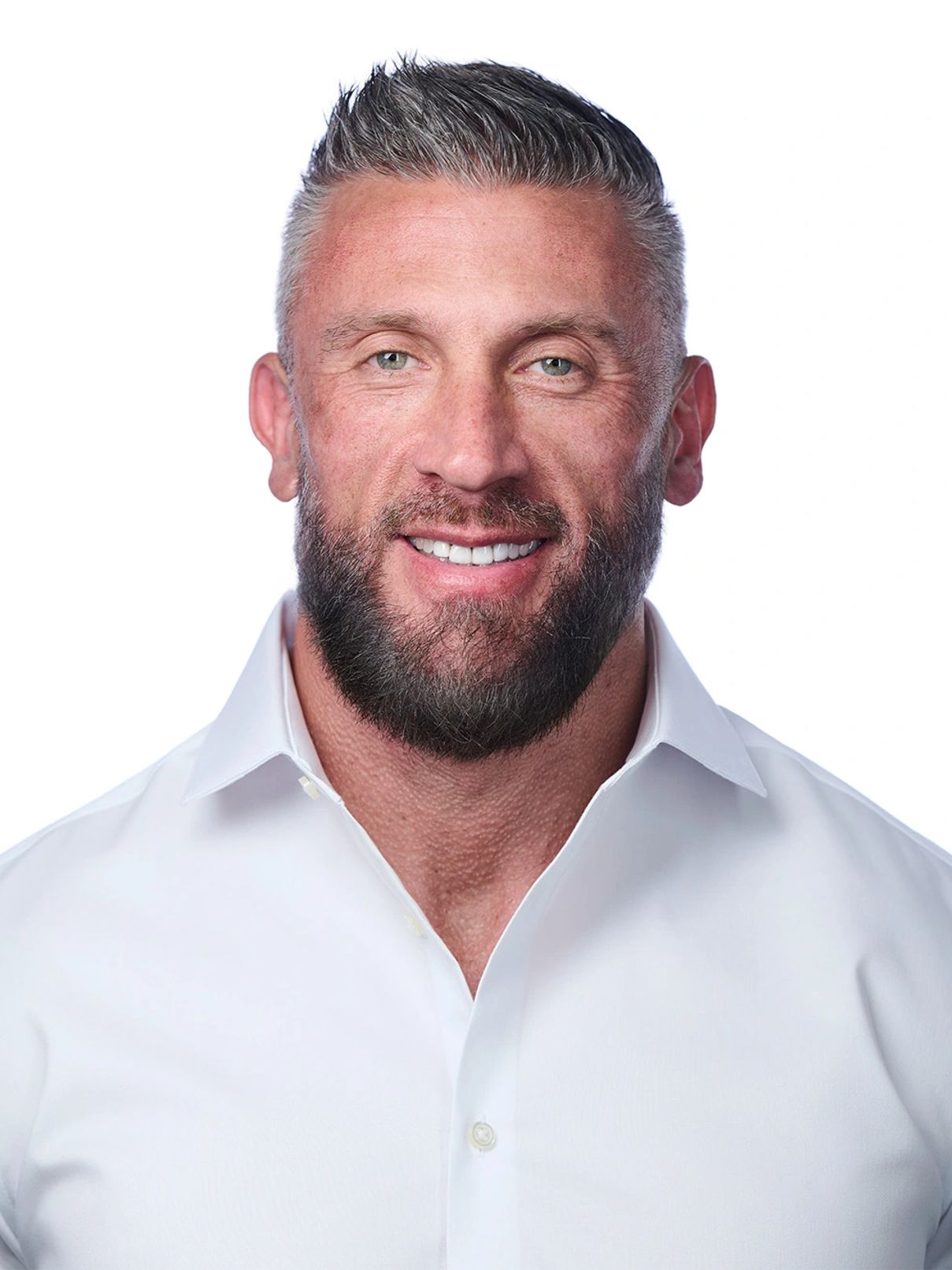 Smiling man with a beard wearing a white shirt against a white background.