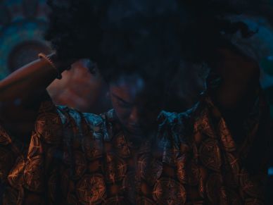 Person adjusting hair in dim light.