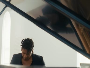 Person playing piano with reflection on the piano lid.