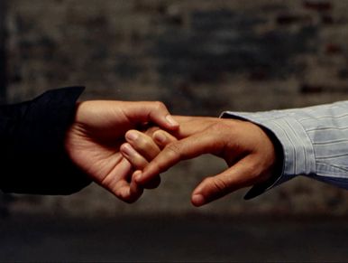 Two hands gently holding each other's fingers.