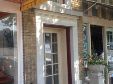 Entrance of a brick building with glass door and floral decorations.