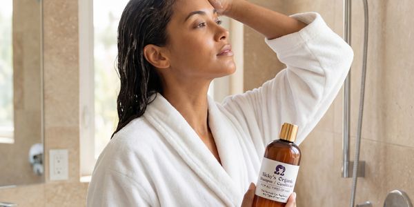 Woman in a white robe holding a skincare product in a bathroom.