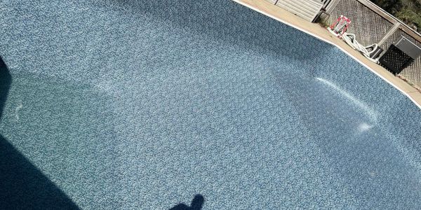 Empty swimming pool with a textured blue surface in bright sunlight.