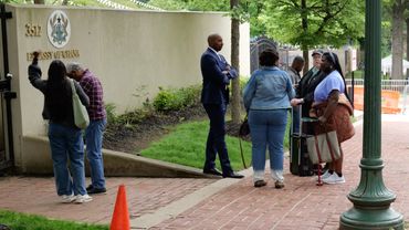 People gathered outside the Embassy of Ghana, some with luggage.