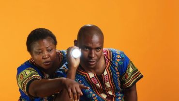 Two people in colorful traditional clothing using a flashlight.