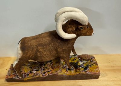 A detailed sculpture of a bighorn sheep on a rocky base.