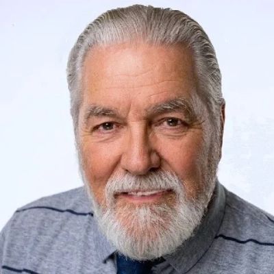 Portrait of a smiling elderly man with gray hair and beard.