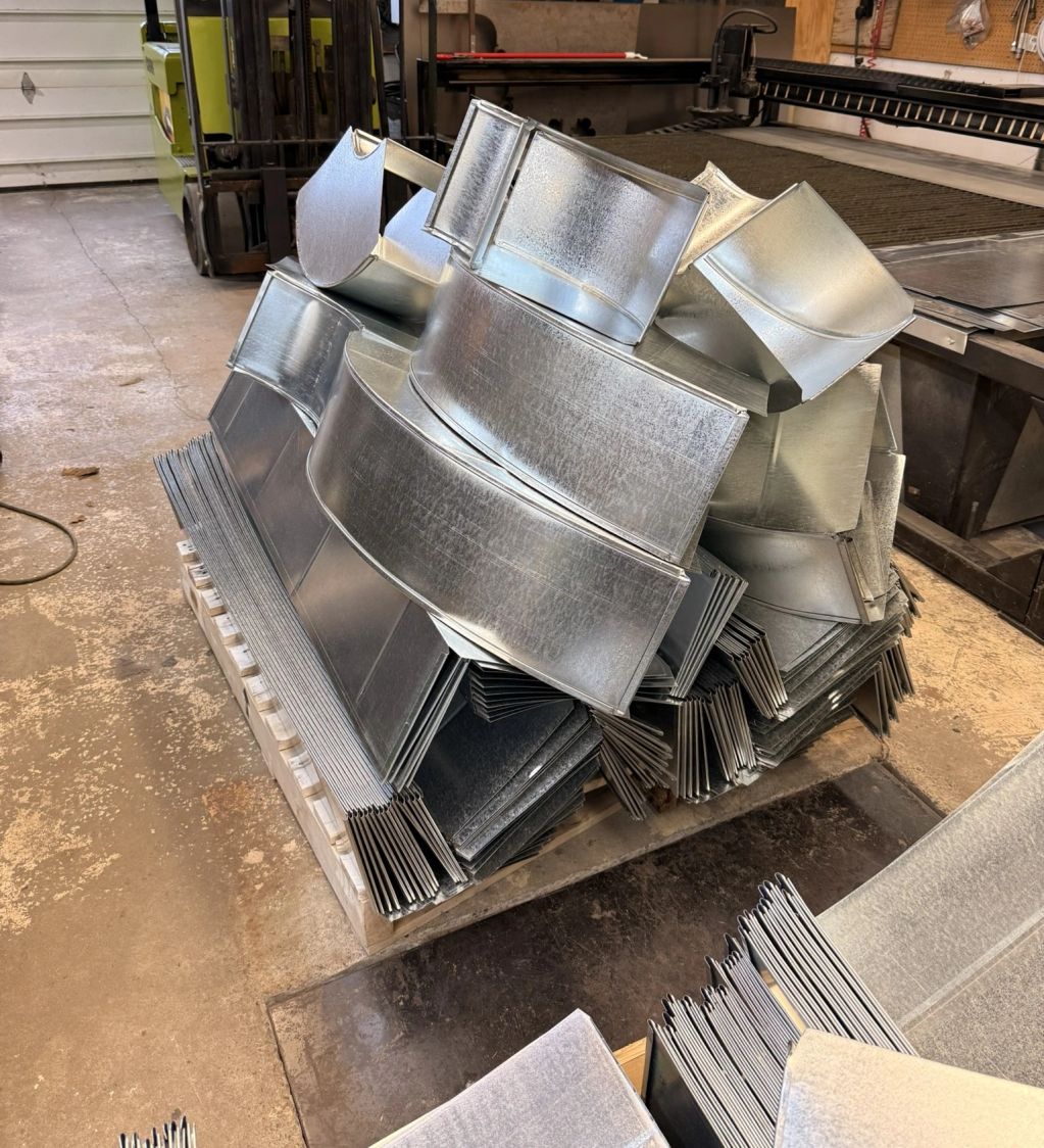 Stack of metal ductwork pieces in a workshop.