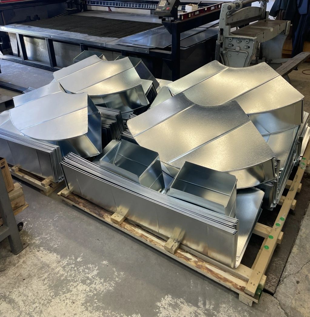 Stacked metal duct pieces in a workshop.