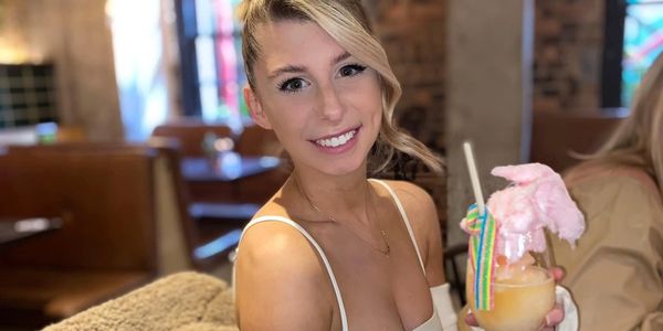 A young lady with a cocktail looks happy and vibrant as she enjoys her evening in a restaurant.