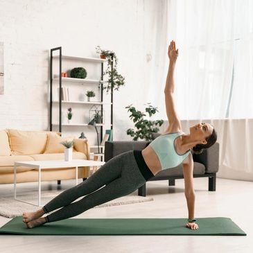Yoga enthusiast practicing her side plank in her light and spacious living room.