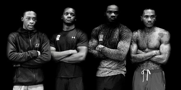 Four men standing confidently with arms crossed, dressed in athletic wear.