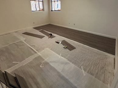 Room in progress of installing new wooden flooring with tools scattered.