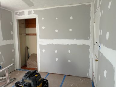 Interior room under drywall installation with patches and taped seams.