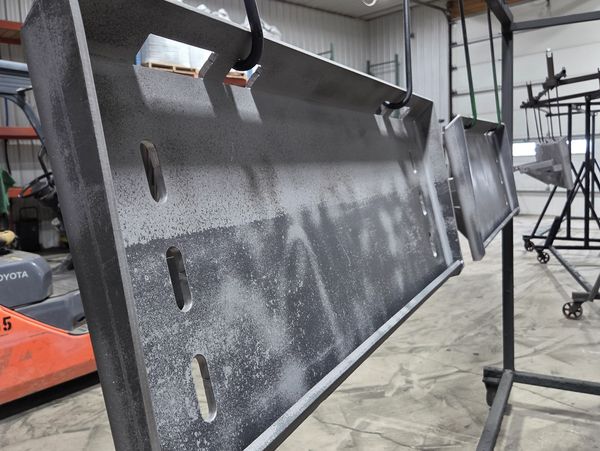 Metal parts hanging in a workshop, drying or curing after coating.