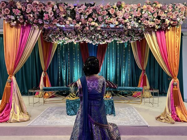 four poster mehedni stage with floral runners and bright drapes.