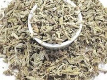 Dried herbal leaves in a pile with a small white bowl on top.