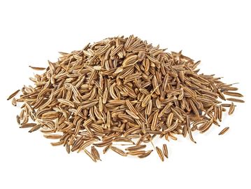 Pile of dried cumin seeds on a white background.