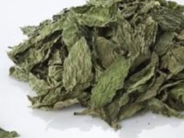 A pile of dried green leaves on a white surface.