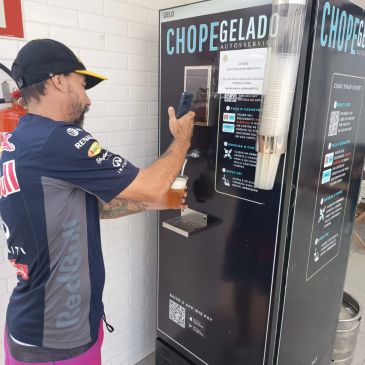 Homem tirando chope gelado de máquina automática.