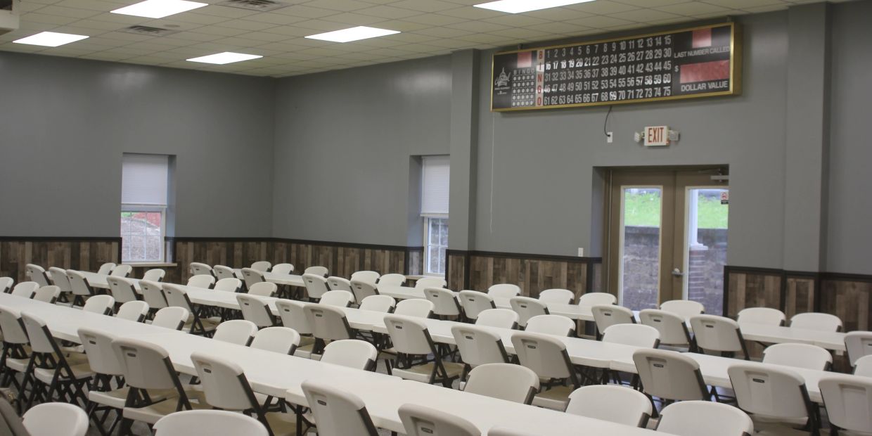 Empty bingo hall with white tables and chairs.