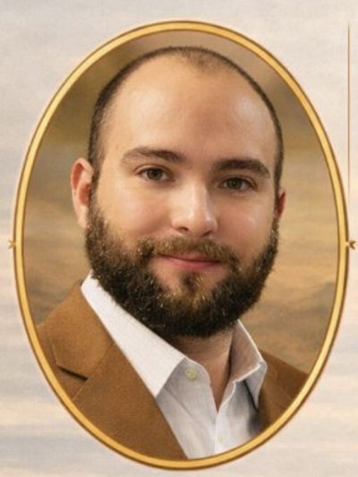 Portrait of a smiling man with a beard and brown jacket.