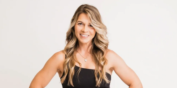 Smiling woman with long wavy hair in a black sleeveless top.