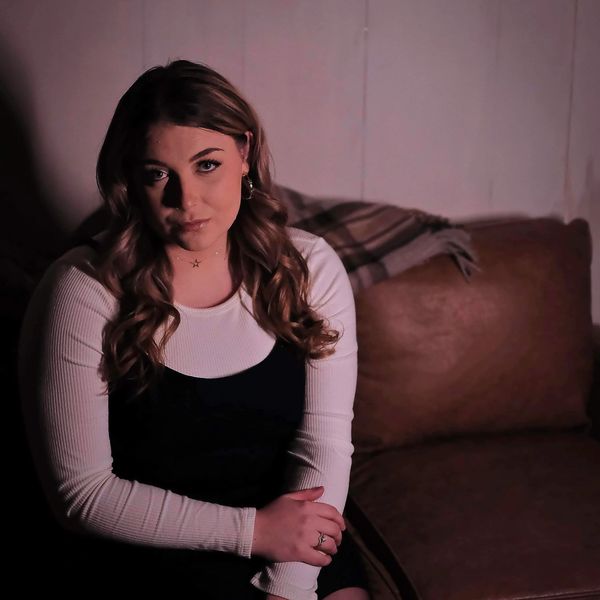 Woman sitting on a couch with a serious expression.