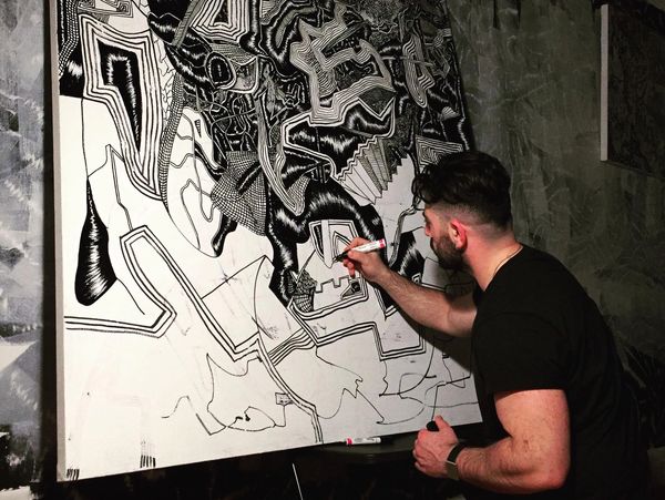 Man drawing on a large abstract black-and-white canvas.