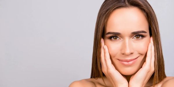Close-up of a smiling woman with hands on her cheeks.