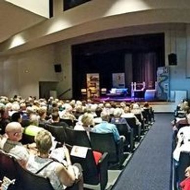 Audience seated in a theater facing a stage.