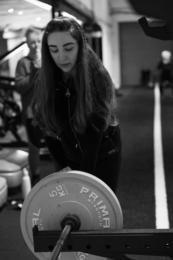 A woman setting weights on a barbell in a gym.