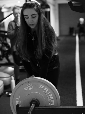 Woman preparing to lift weights in a gym setting.