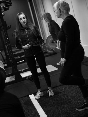 Two women exercising and interacting in a gym setting.