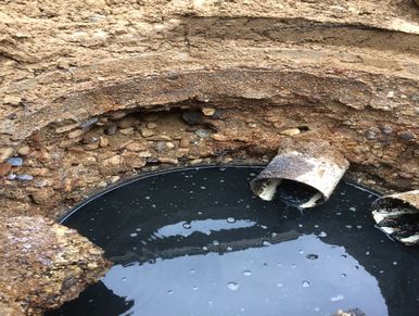 Broken pipe discharging into a muddy water pool in an excavation.