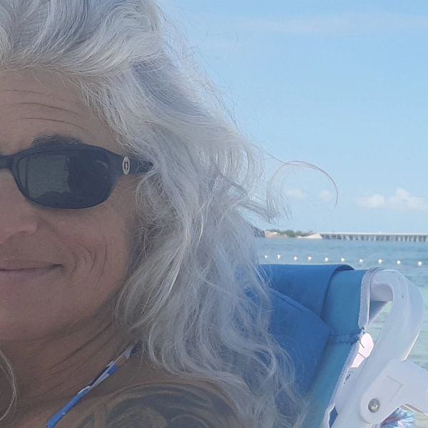 Woman with white hair at the beach on a sunny day.