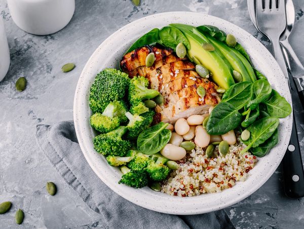 Healthy green vegetable bowl with grilled chicken, quinoa, spinach, avocado, broccoli & white beans.